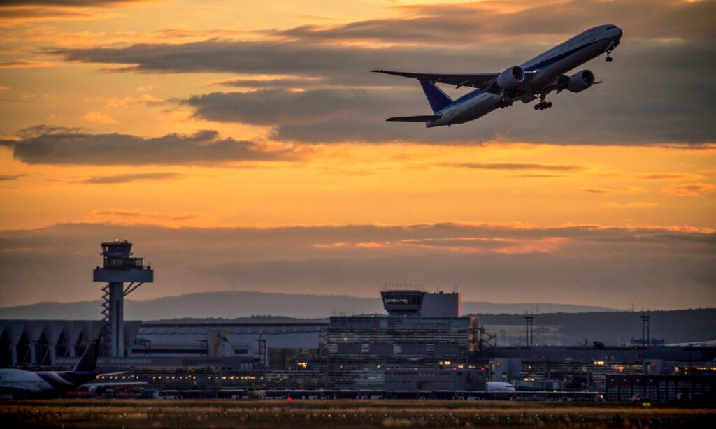 Startendes Flugzeug in Frankfurt in der Abenddämmerung